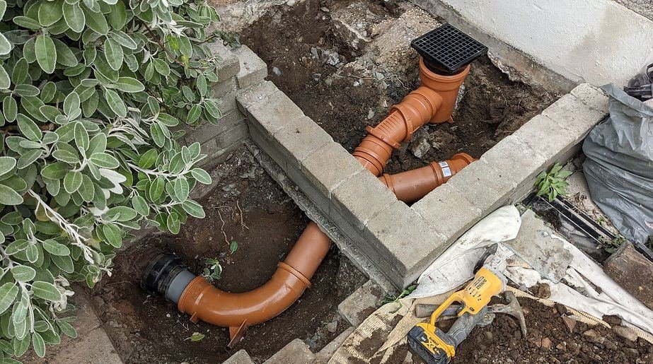 New drainage connection and gully installed beside a garden wall